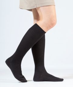 Chaussettes hautes en laine mérinos noires portées de façon élégante dans un studio, mettant en valeur leur couleur et leur texture douce et respirante.